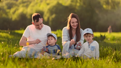 Family-of-4-two-children-and-parents-eat-ice-cream-in-the-summer-on-a-picnic.